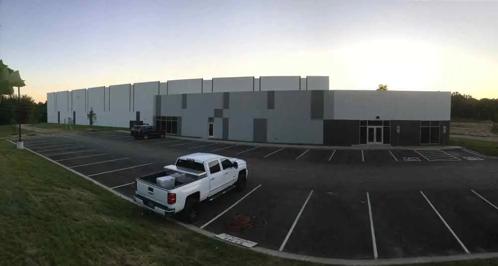 A truck parked in the parking lot of an industrial building.